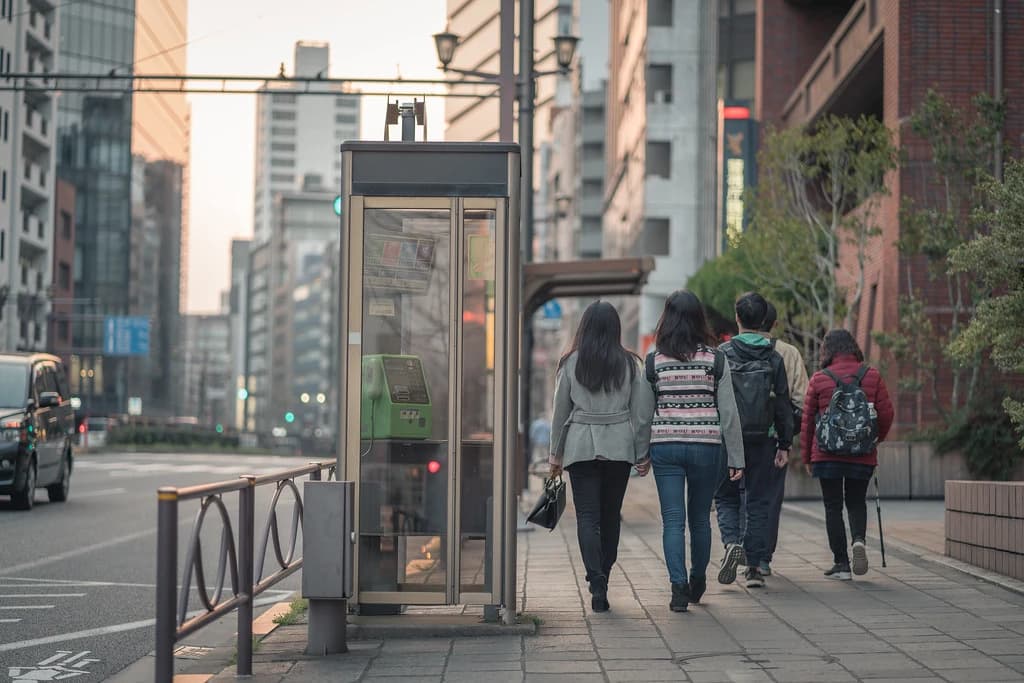 歩道を歩く人と電話ボックス